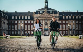 Tretty GmbH | Pexels Couple cycling in front of Münster Castle.