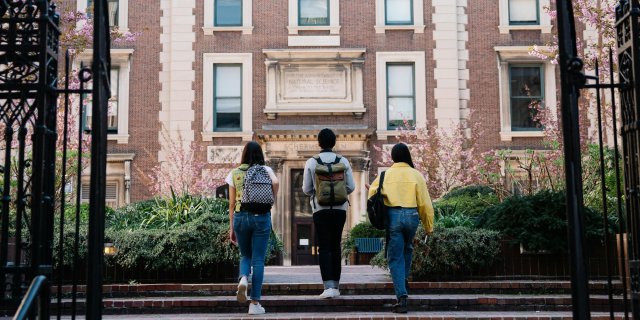 Three students approach a university building.