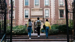Three students approach a university building.