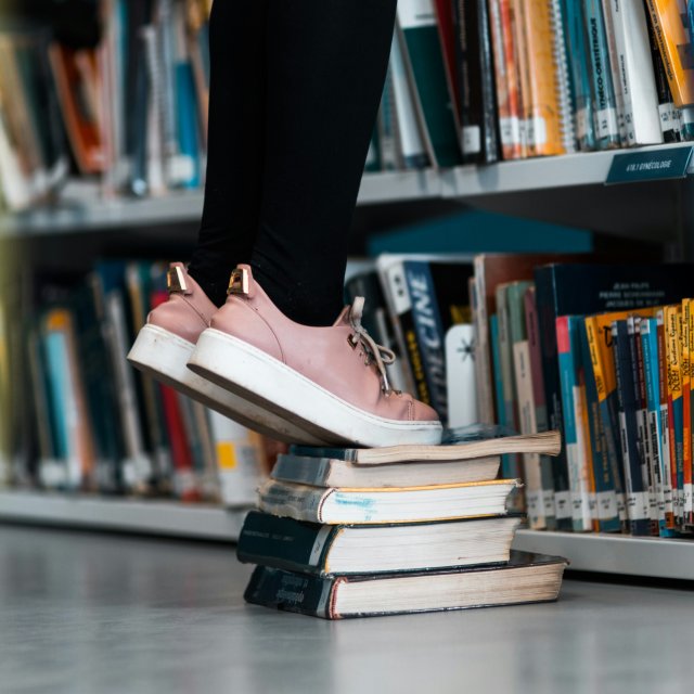Someone stands on a stack of books.